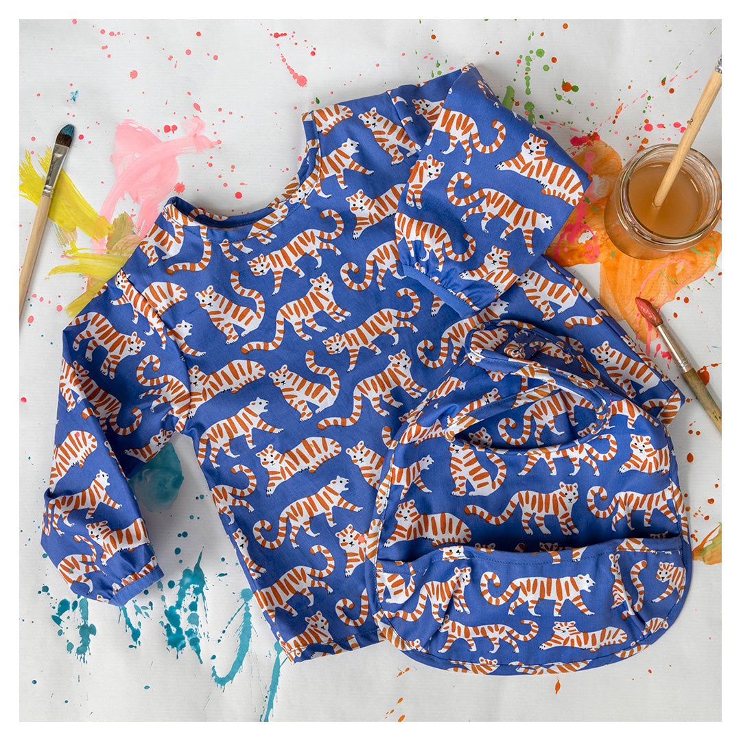 Rex London kinderschort en slab met blauw tijgerpatroon op een ondergrond met verfspatten.