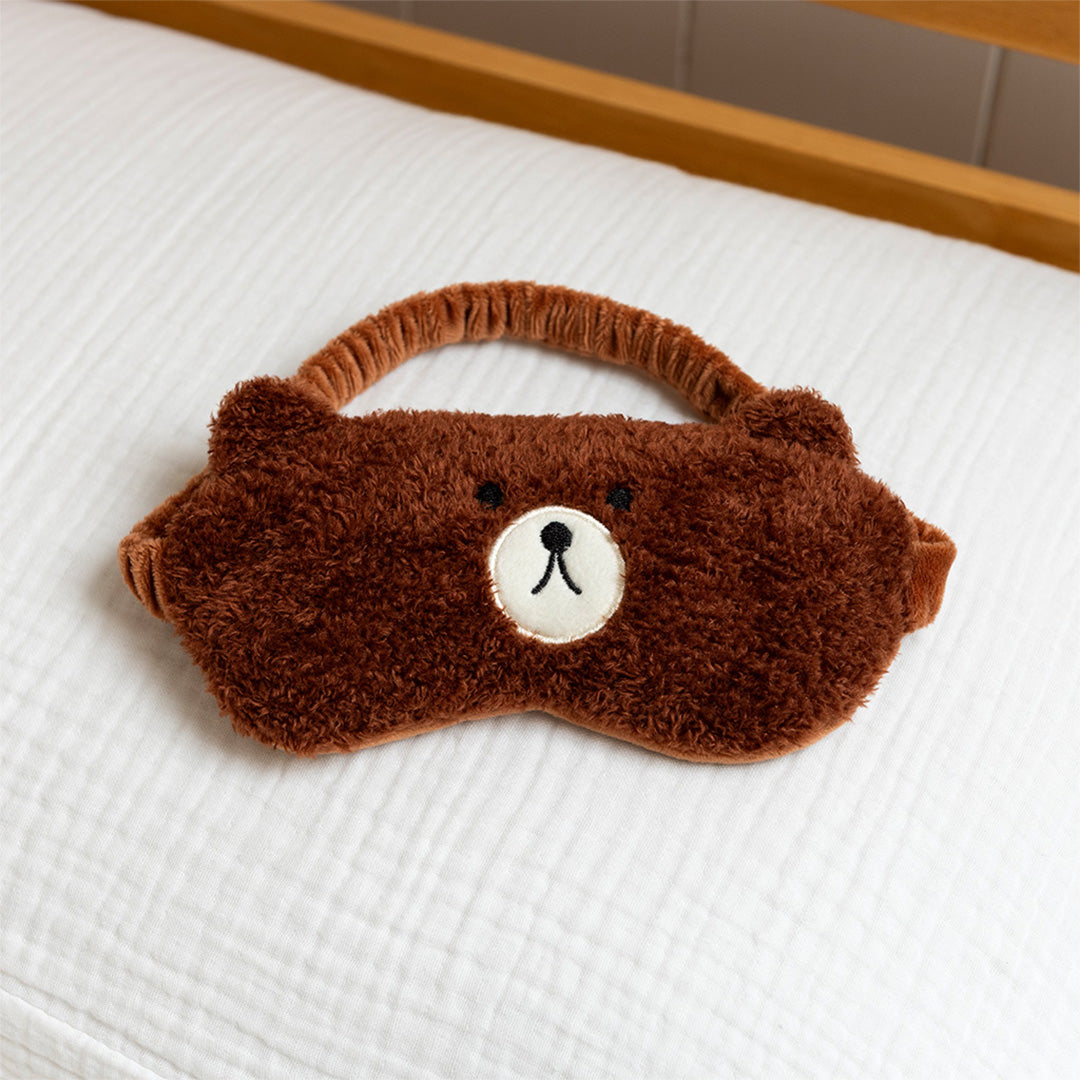 Rex London bruin pluche slaapmasker met beergezicht op een wit bed.