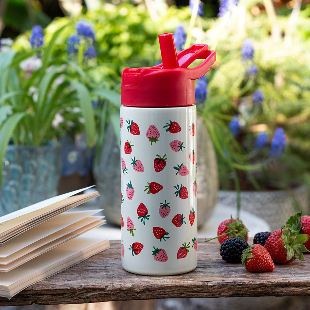 Rex London drinkfles met aardbeipatroon op een houten tafel met fruit en een open boek.
