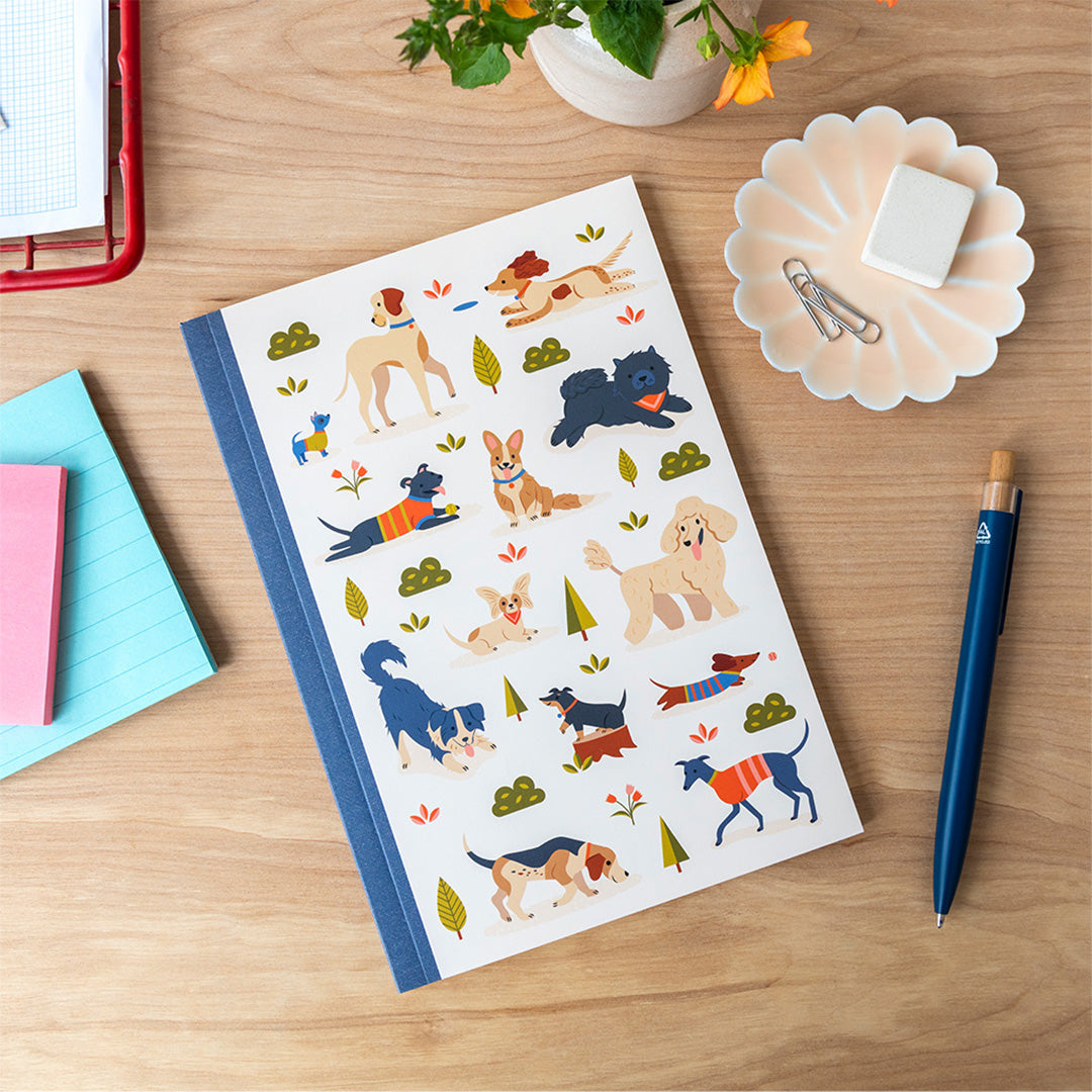 Rex London A5 schrift met hondenillustraties ligt op een houten bureau met een pen en notitieblokjes.