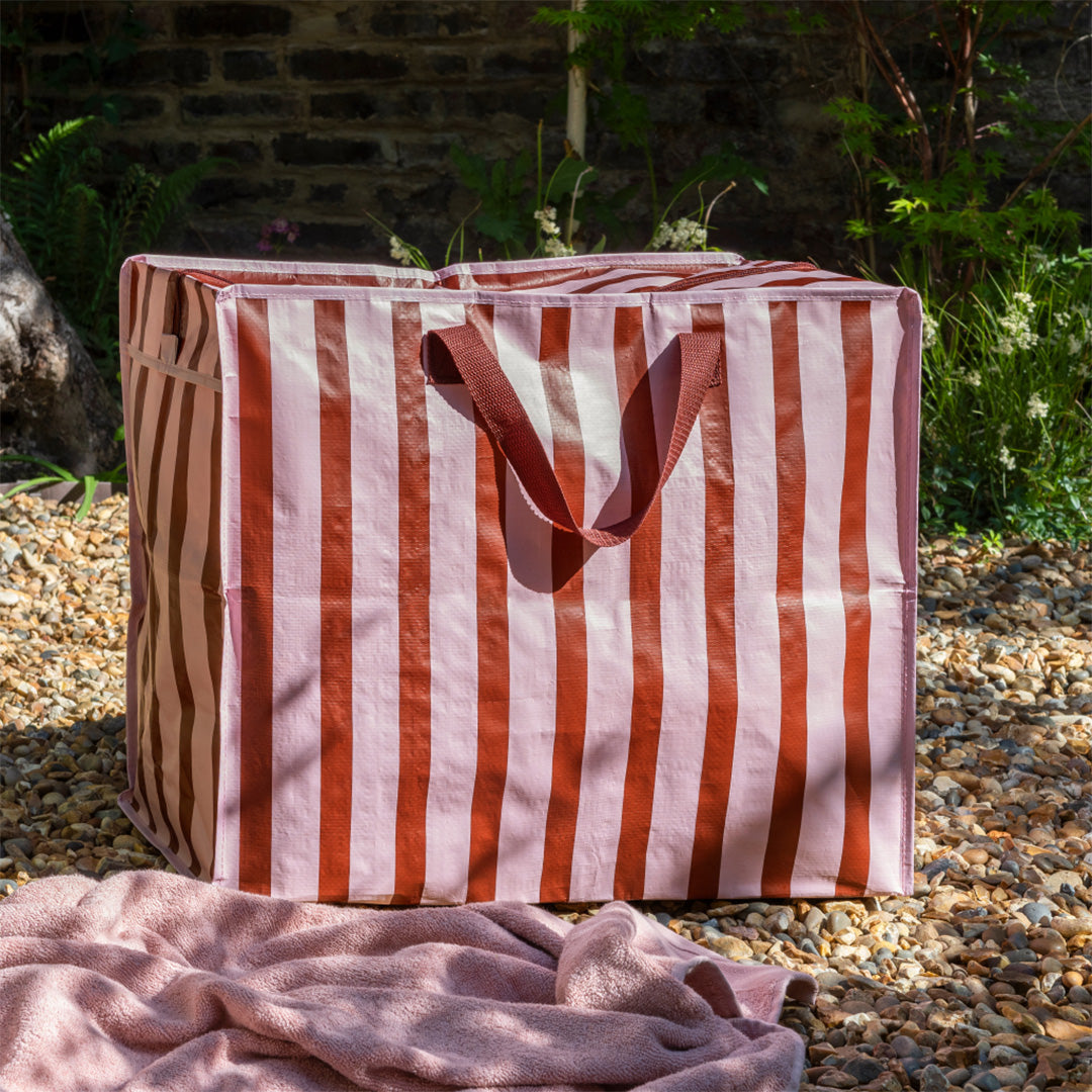 Rex London jumbo opbergtas met roze en bruine strepen staat buiten op een grindpad.