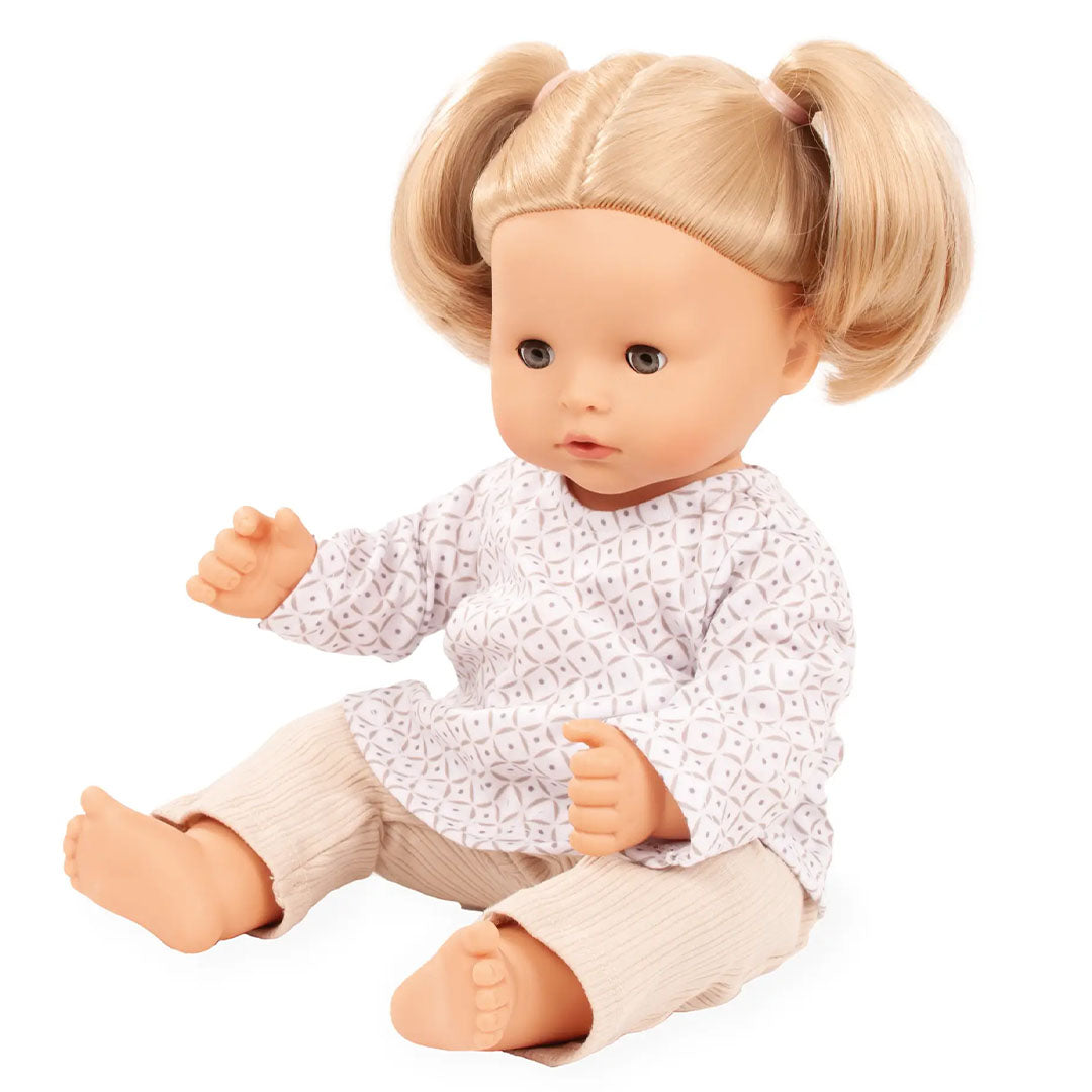 Gotz pop met blonde staartjes draagt de poppenkleding set met wit topje met geometrisch patroon en beige geribbelde broek.