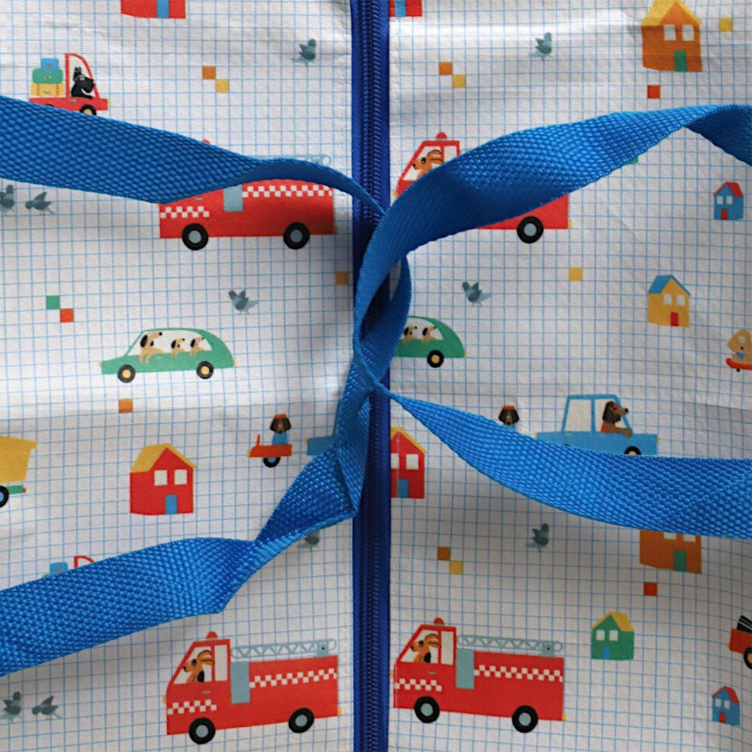 Detail van de le petit souk opbergtas met blauwe handvatten en een patroon van voertuigen en honden.