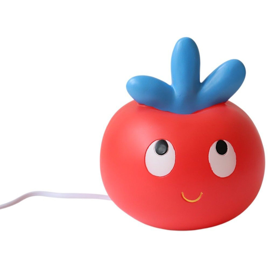 Le Petit Souk kinderlamp in de vorm van een rode appel met blauwe blaadjes en een vrolijk gezicht, brandend.