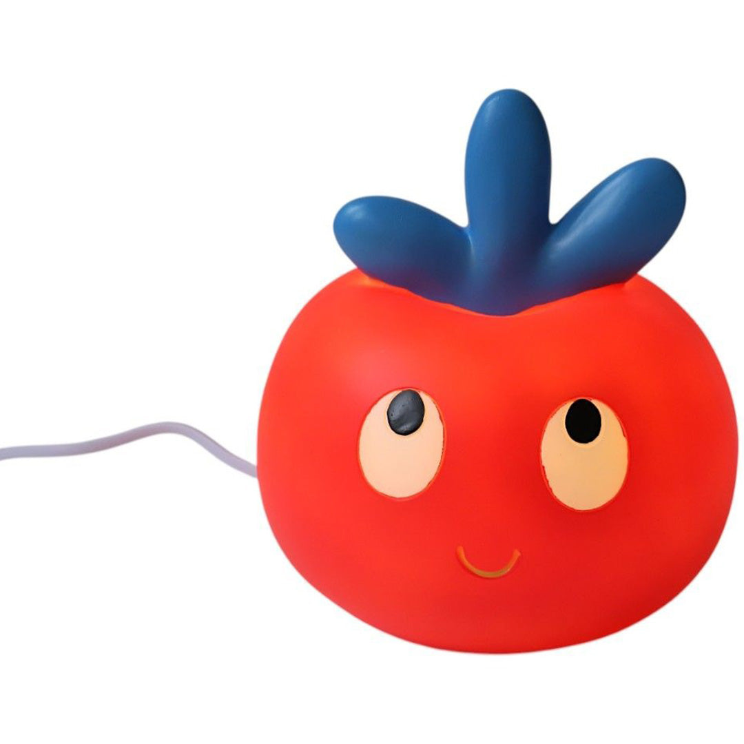 Le Petit Souk kinderlamp in de vorm van een rode appel met blauwe blaadjes en een vrolijk gezicht, brandend.