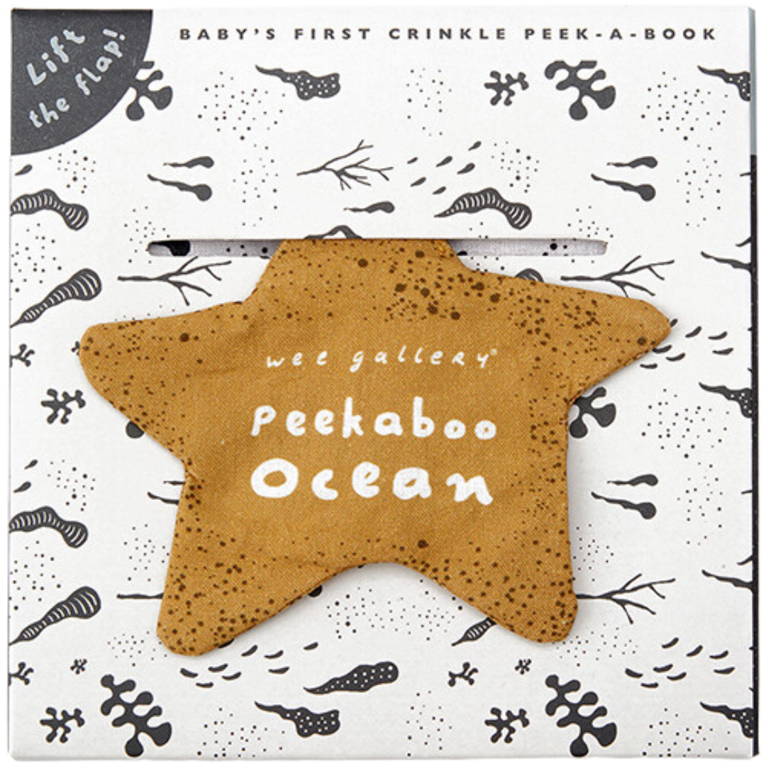 De voorkant van de verpakking van het Wee Gallery Peekaboo Ocean knisperboekje, met een beige ster-vormige flap en oceaanpatronen.
