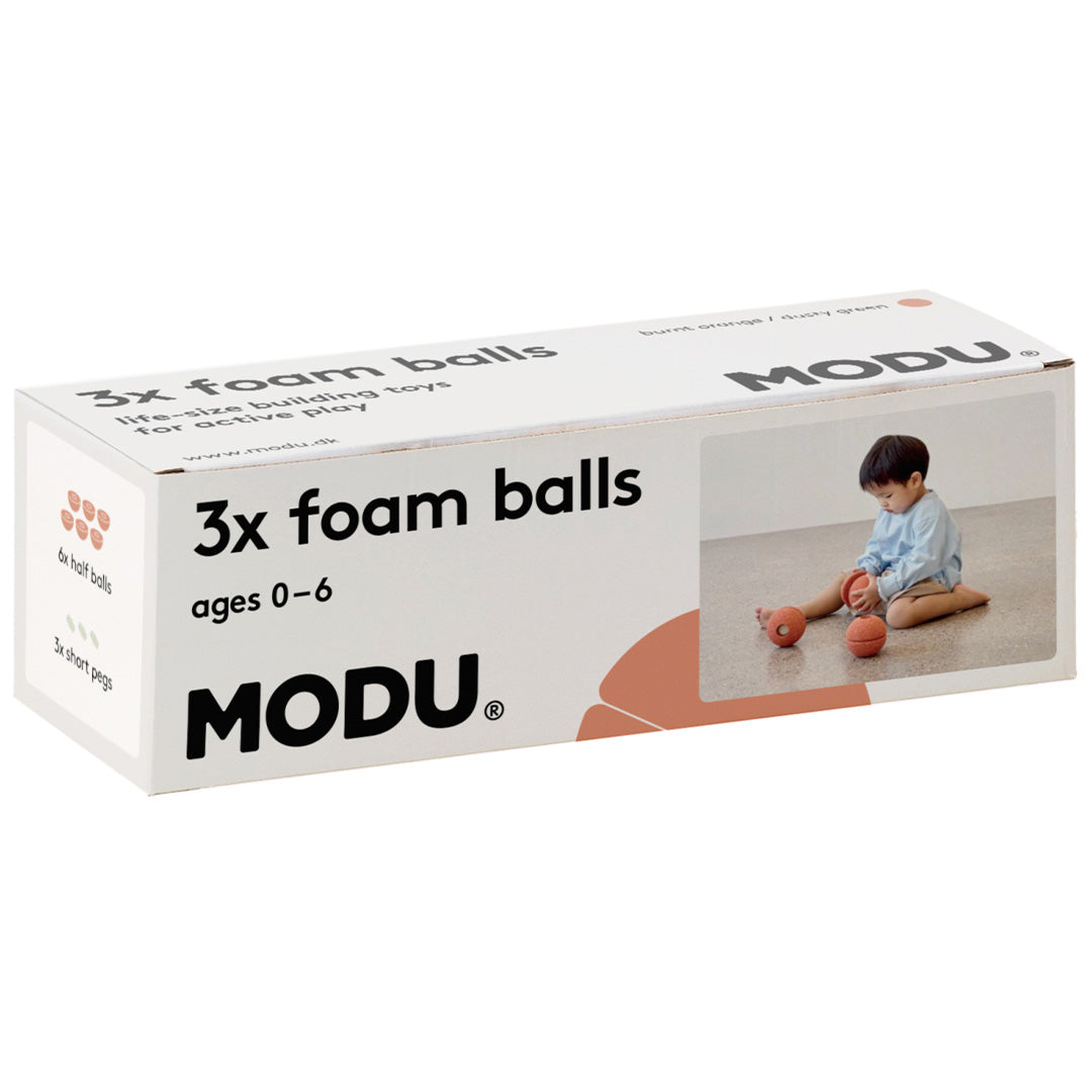 De verpakking van de Modu 3x foam balls, met een afbeelding van een spelend kind.
