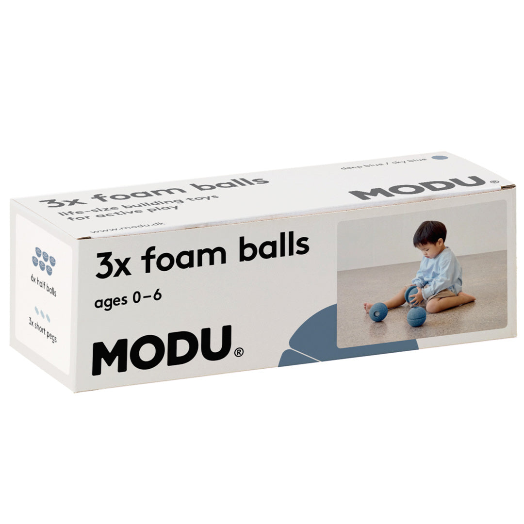De witte verpakking van de Modu 3x foam balls, met productinformatie en een afbeelding van een spelend kind.