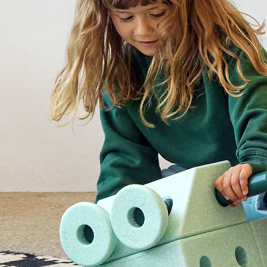 Een kind speelt met Modu bouwspeelgoed van schuim in ocean mint kleur.
