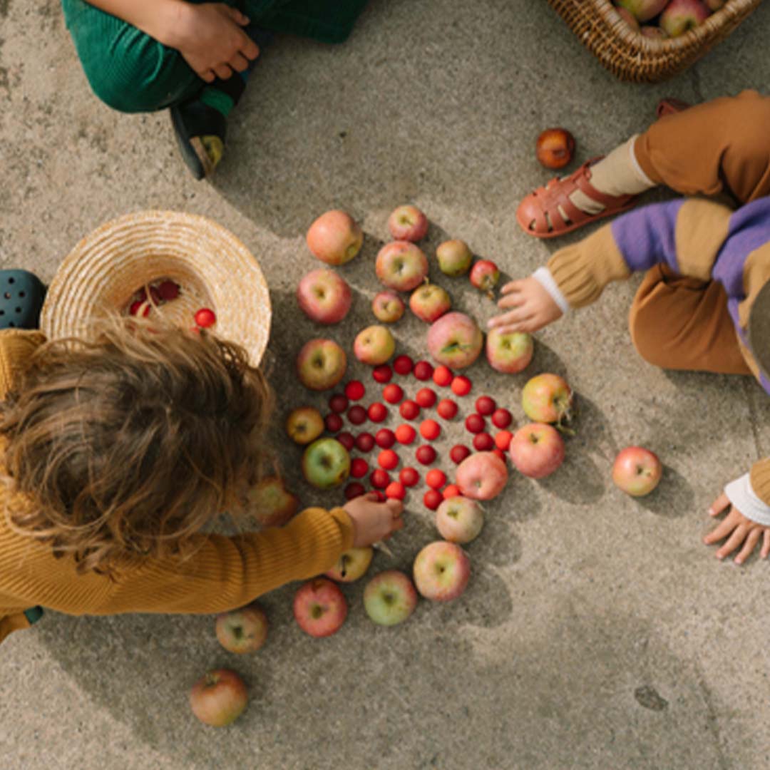 Twee kinderen spelen buiten met Grapat houten halve bollen en appels.