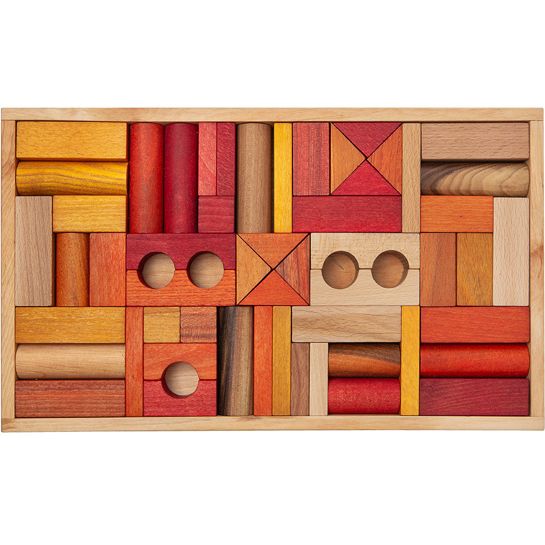 Wooden Story houten bouwblokken in warme tinten rood, oranje en naturel, gerangschikt in een houten bak.