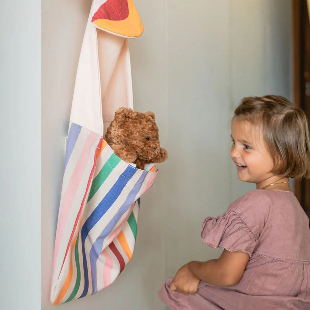 Een kind kijkt naar een teddybeer in de play&go eenhoorn wandopberger en draagtas.