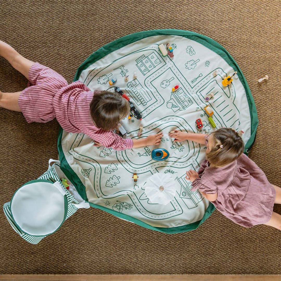 Twee kinderen spelen met speelgoedauto's op het play&go speelkleed met wegenkaart.