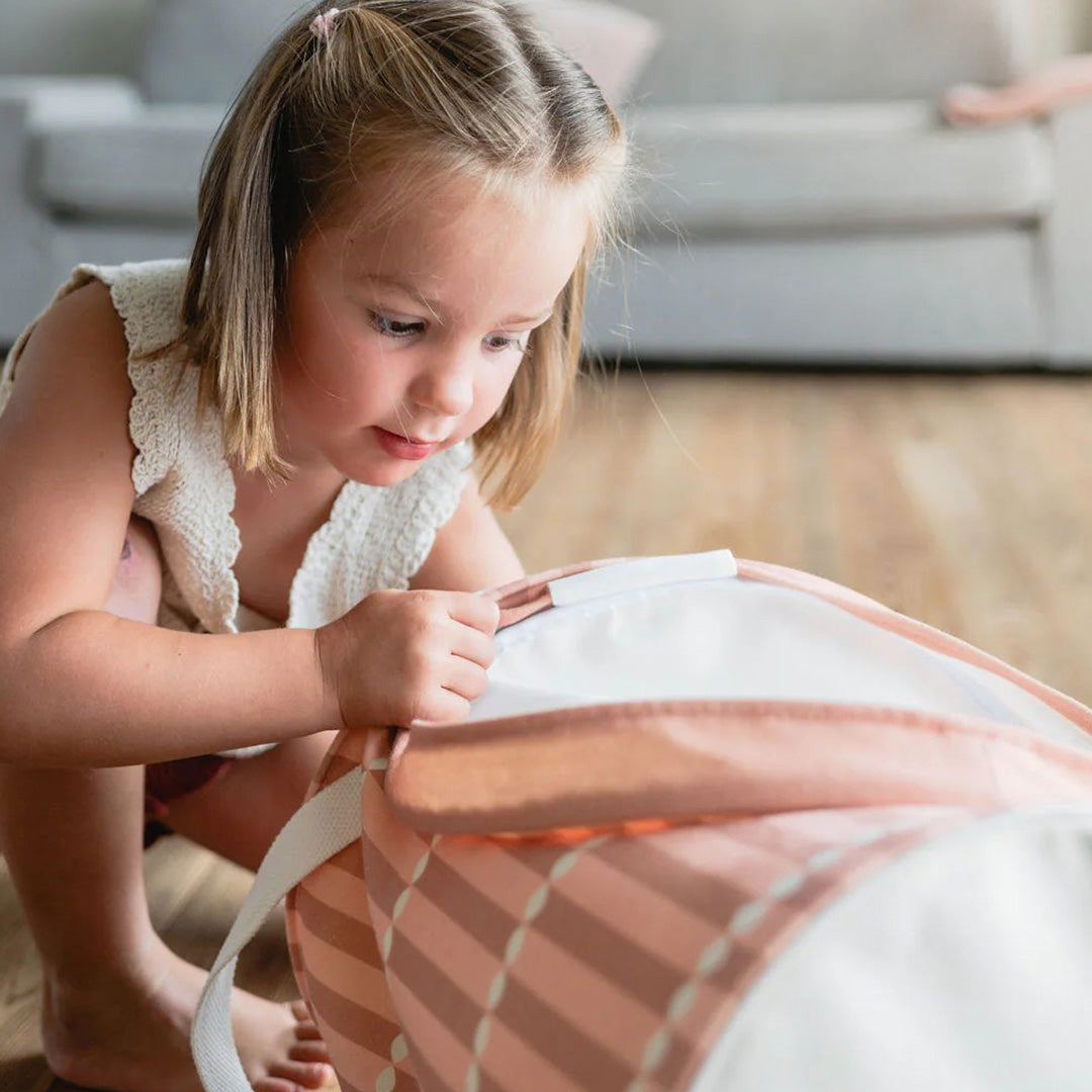 Een kind sluit de play&go opbergmand met gestreept patroon.