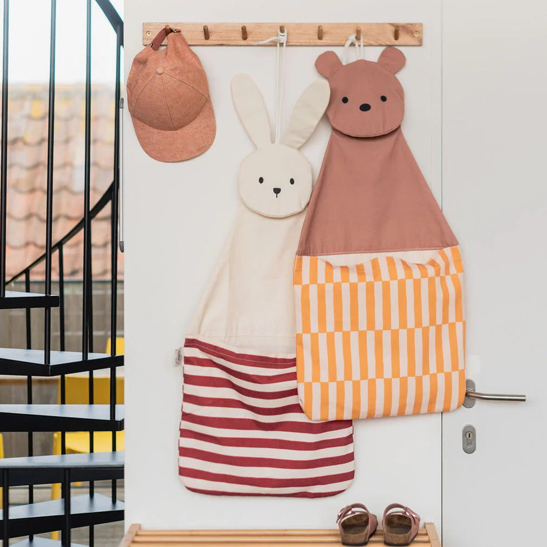 Twee play&go wandopbergers, een konijn en een beer, hangen naast elkaar aan een houten kapstok.