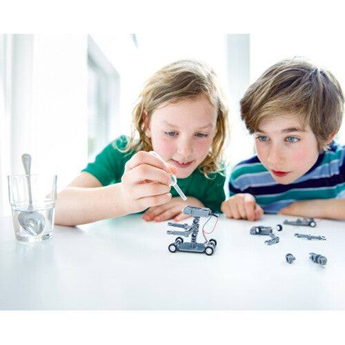 Twee kinderen bouwen of activeren de 4M zout water robot met een druppelaar.