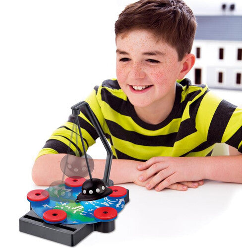 Een jongen kijkt lachend naar een magnetisch levitatie experiment met een zwevend UFO-object.
