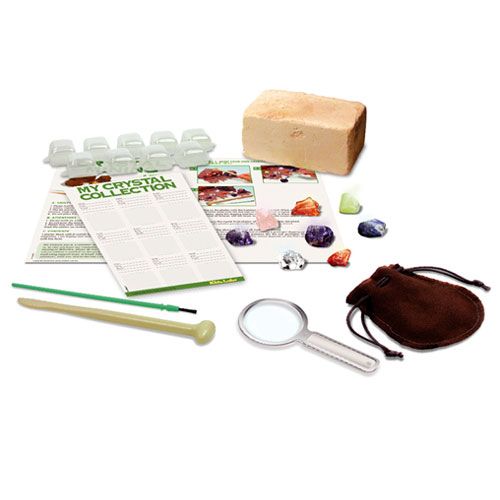 Alle onderdelen van de 4M KidzLabs Crystal Mining opgraafkit liggen uitgestald, inclusief blok, gereedschap, vergrootglas en kristallen.