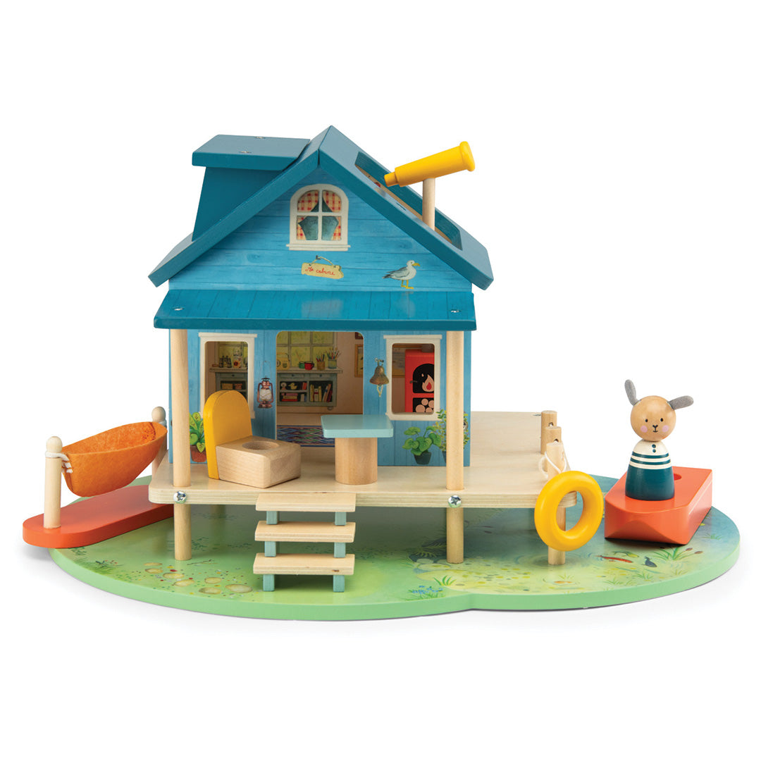 Moulin Roty houten poppenhuis 'huis aan het meer' met een konijnenfiguur, oranje hangmat en bootje.