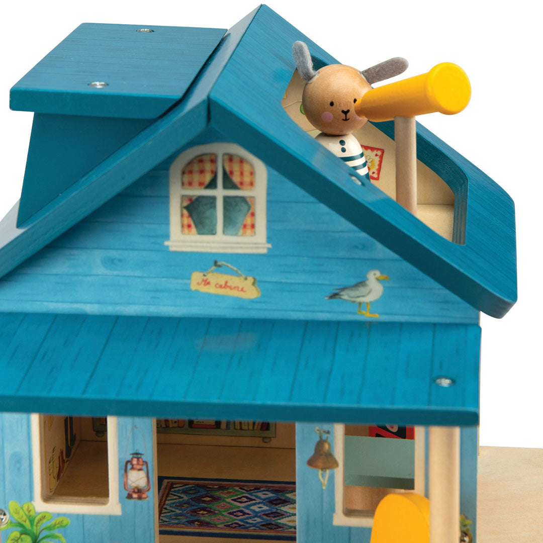 Detail van het Moulin Roty houten poppenhuis 'huis aan het meer' met een konijnenfiguur die door een telescoop kijkt.
