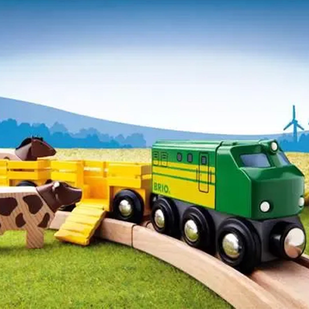 Brio houten speelgoedtrein met boerderijdieren op een houten spoorbaan in een groen landschap.