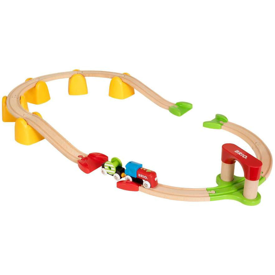 Brio houten treinbaan set met een rode en blauwe speelgoedtrein en diverse accessoires.