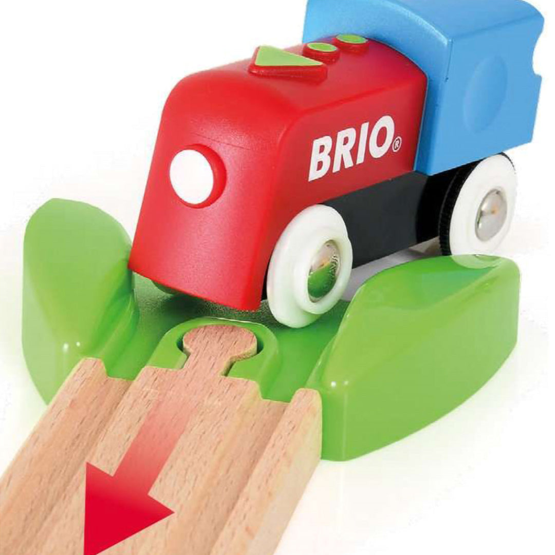 Detail van de rode en blauwe Brio speelgoedtrein op een groen spoorstuk.