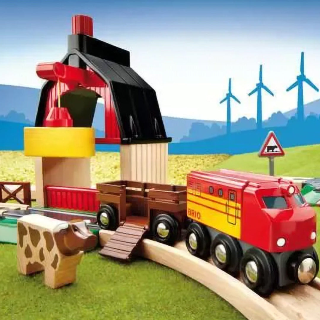 Brio houten treinbaan met een rode trein, een wagon met koe en een schuur, tegen een achtergrond met windmolens.