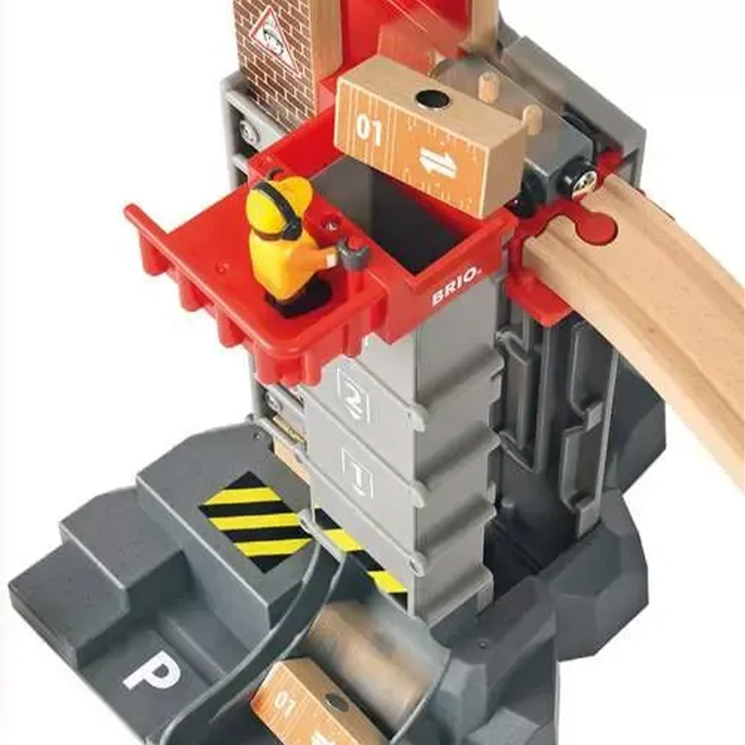 Detail van de Brio treinbaan toren, waar een speelfiguur een houten blok laadt in een rode bak.
