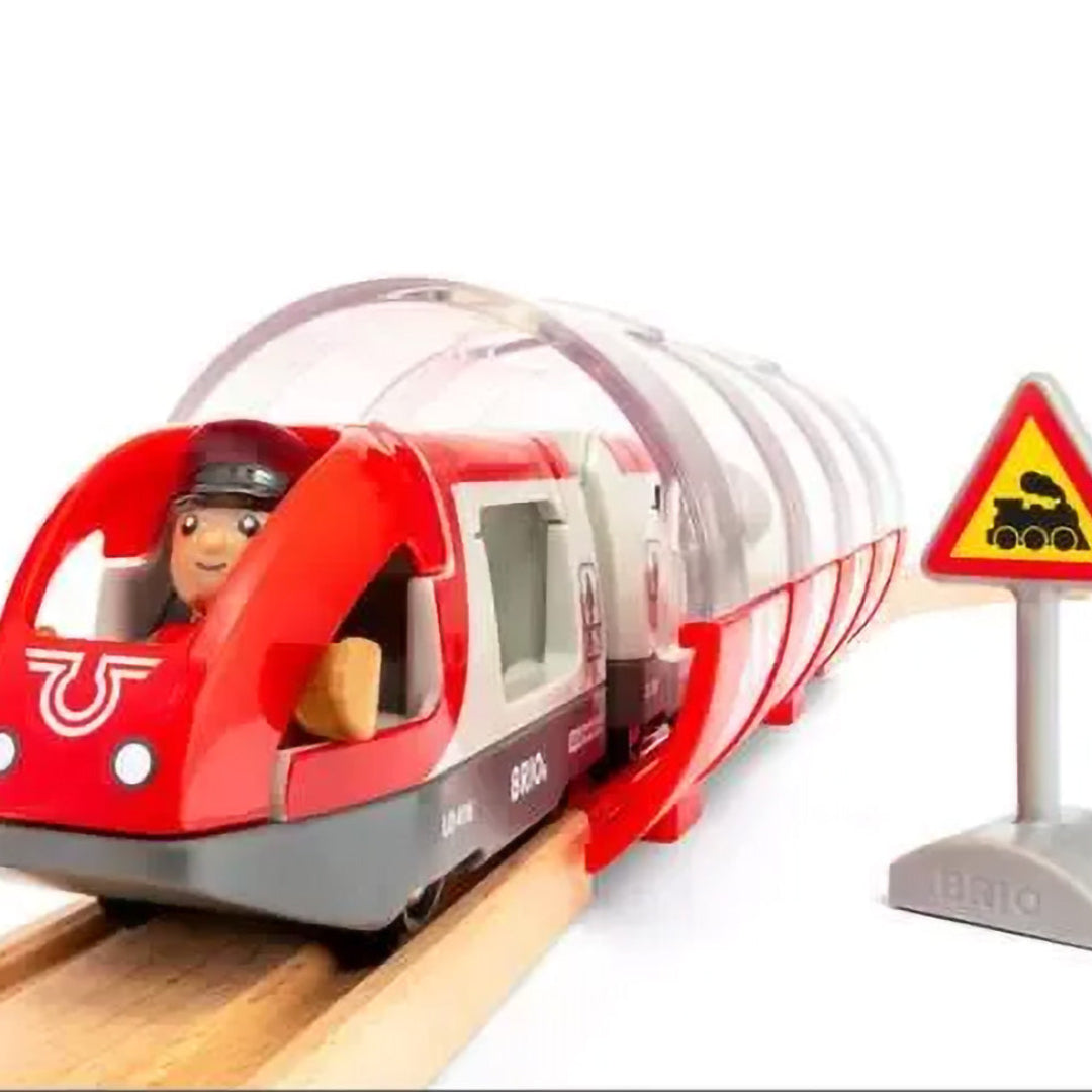 Detail van de Brio treinbaan set met een rode trein met machinist die een tunnel inrijdt.