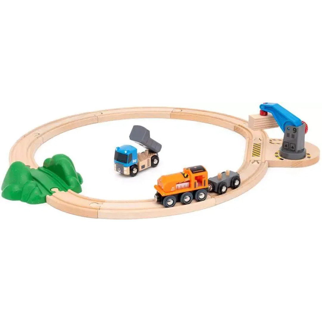 Brio houten treinbaan met oranje trein, blauwe kiepwagen en een kraan op een ronde spoorlijn.