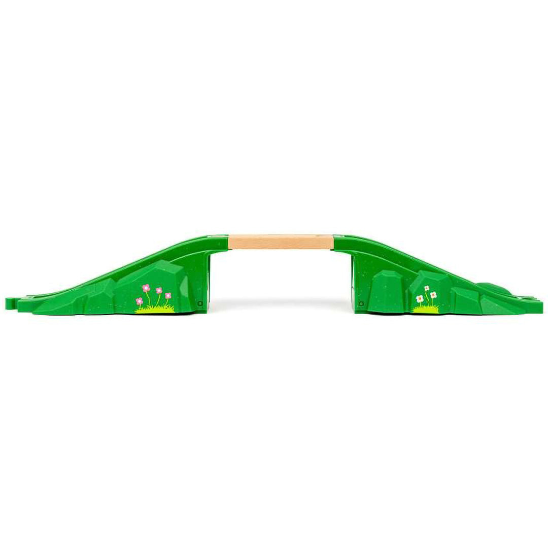 Brio houten en plastic boogbrug voor speelgoedtreinen, met groene hellingen en bloemdecoraties, van voren gezien.