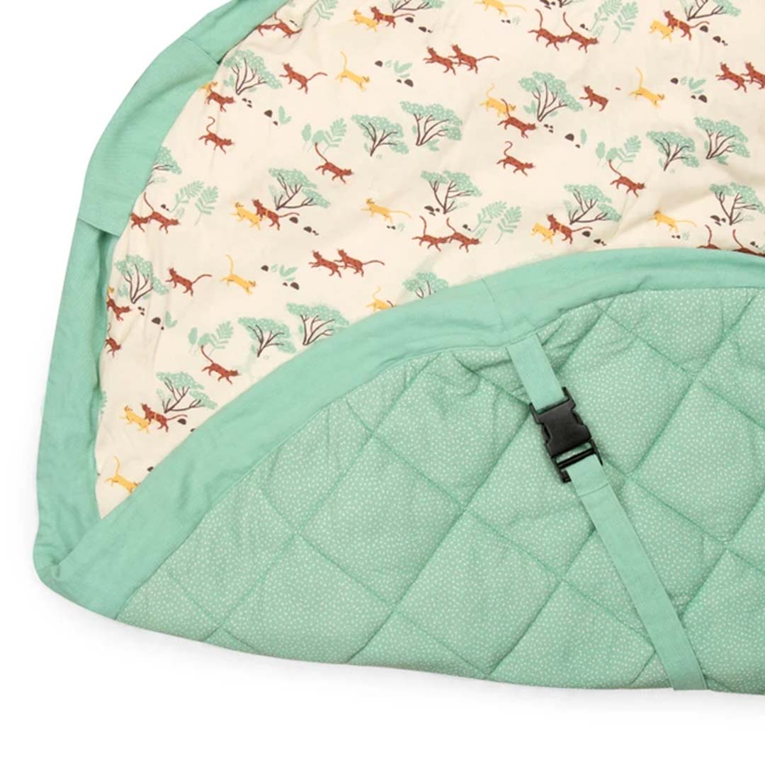 Het play&go speelkleed deels opgevouwen, met de dierenprint en de gewatteerde groene onderkant met gesp.