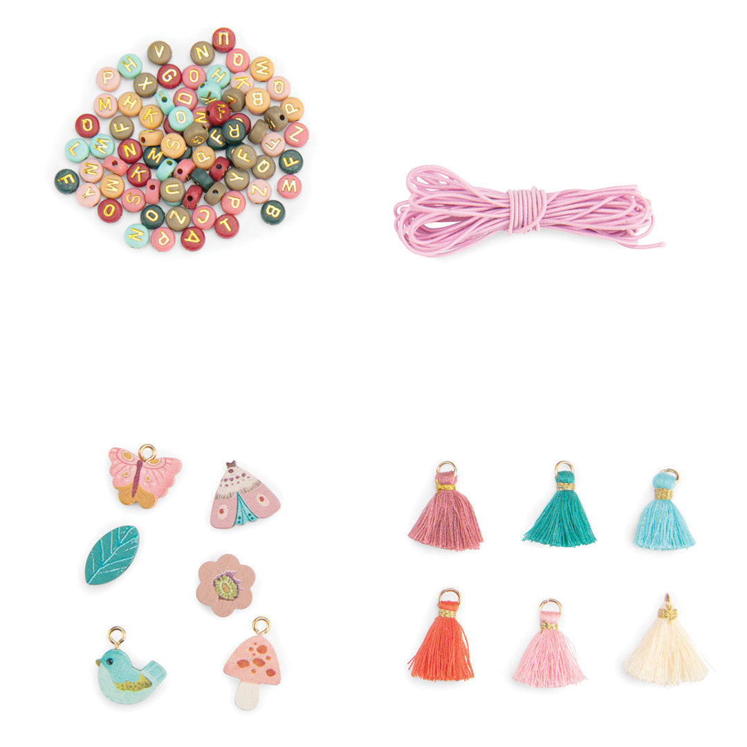 Detail van de Moulin Roty kralenset met letterkralen, roze touw, diverse houten bedeltjes en kwastjes.