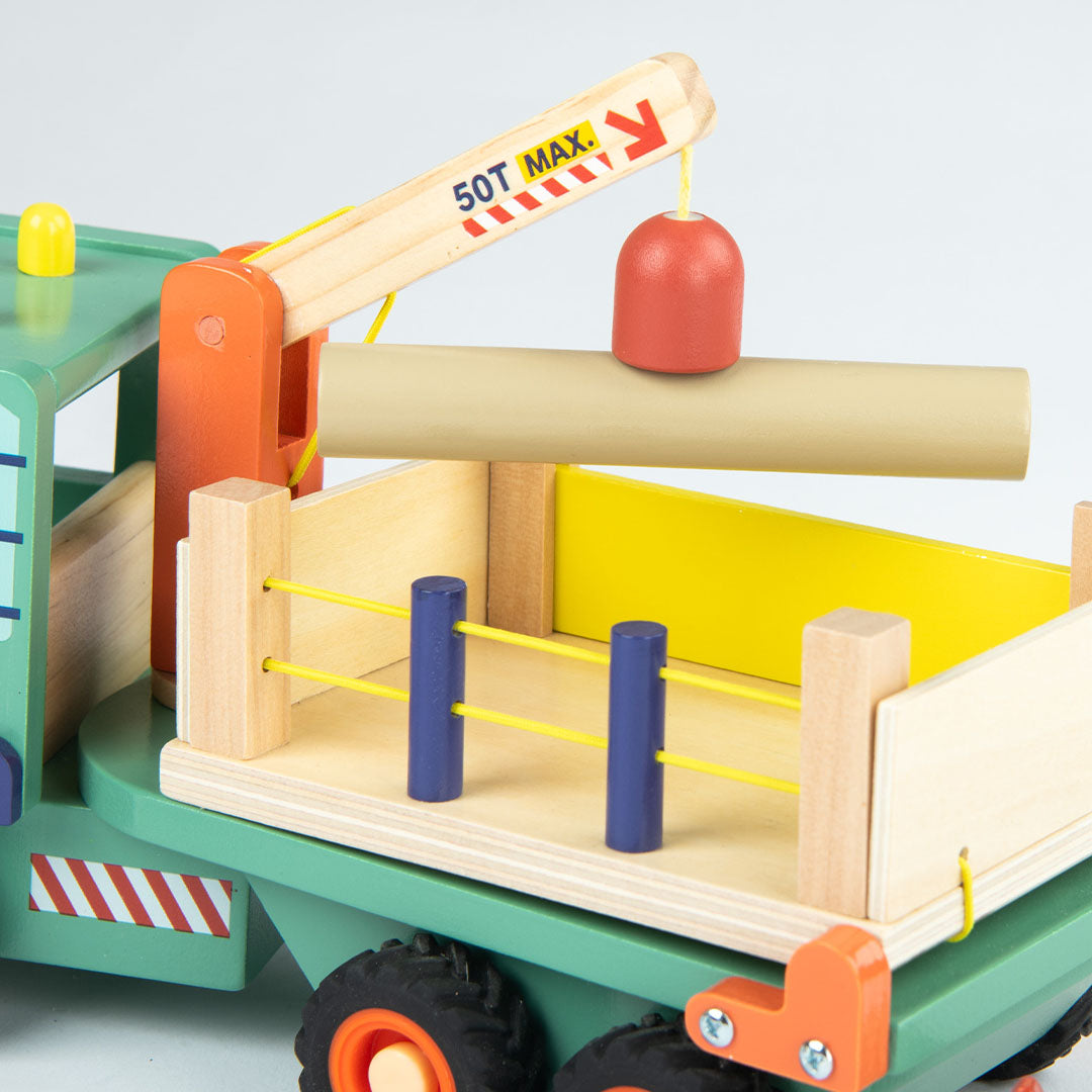 Detail van de kraan en laadbak van de Moulin Roty houten bosbouwvrachtwagen die een boomstam optilt.
