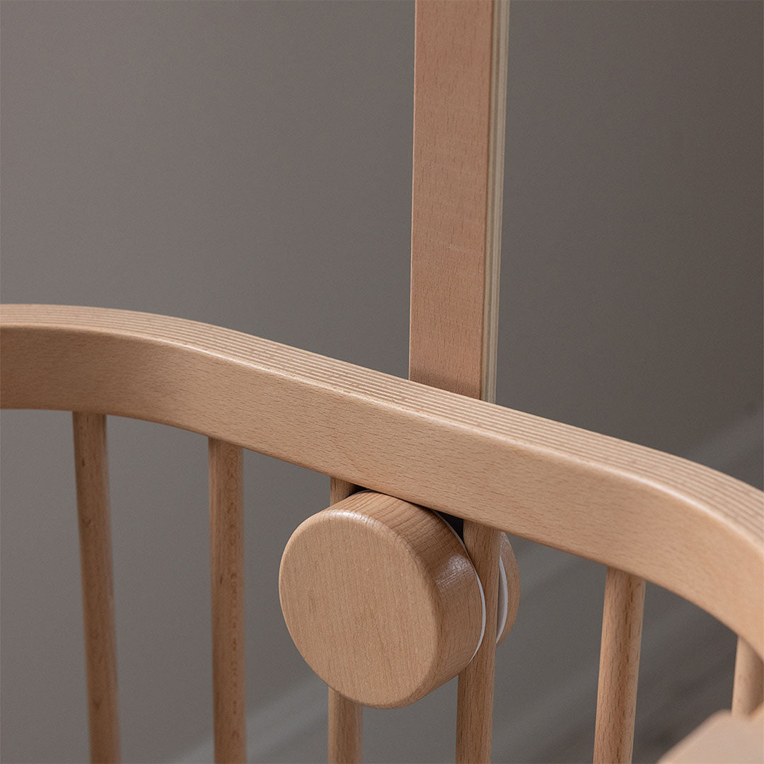 Detail van de Sebra houten mobielhouder bevestiging aan de spijlen van een babywieg.