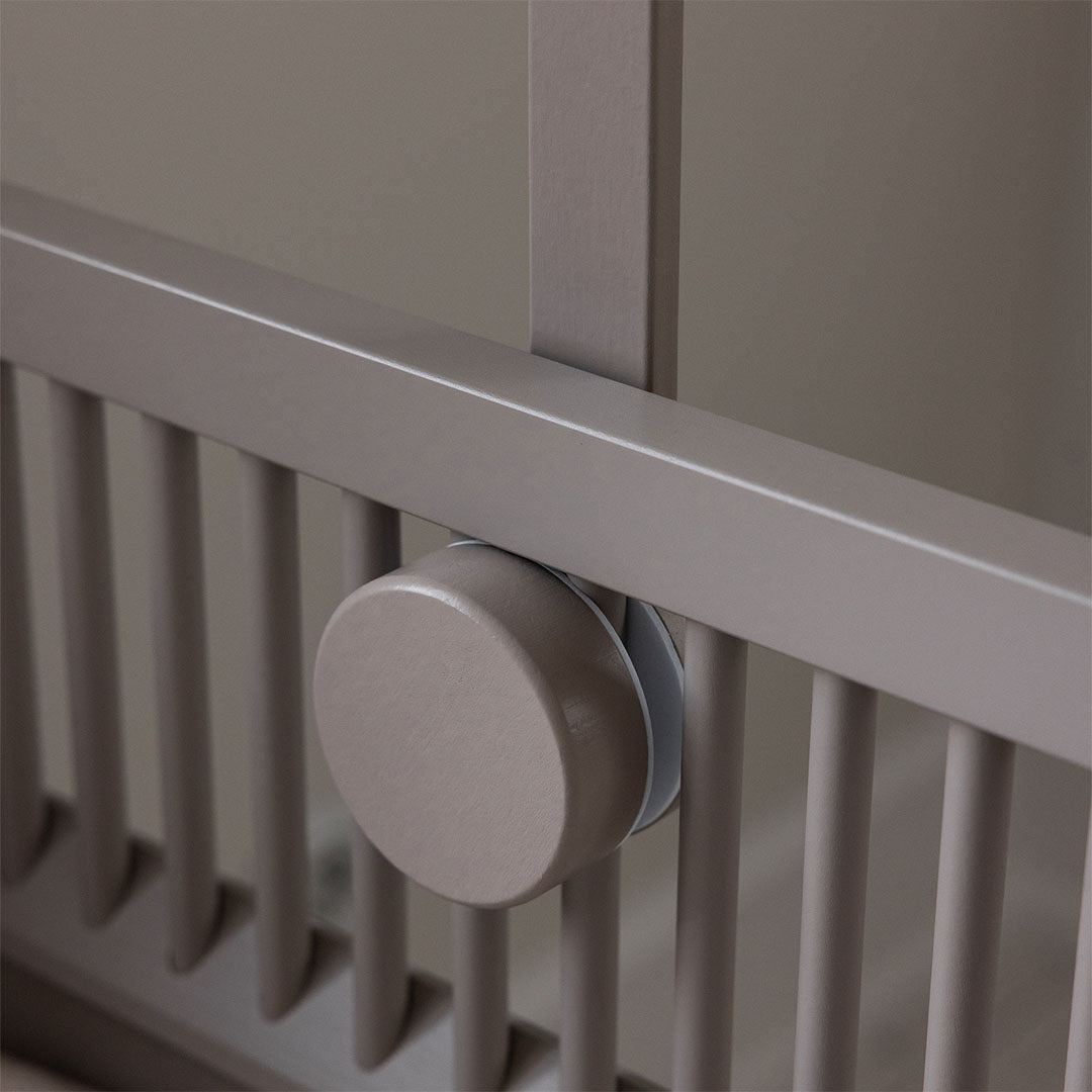 Detail van de beige houten mobielhouder die stevig aan de zijkant van een babywieg is gemonteerd.