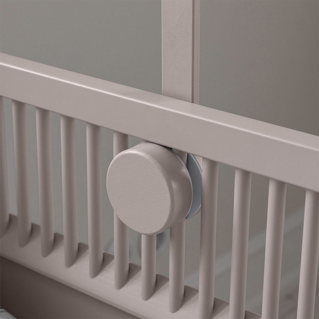 Detail van de Sebra houten mobielhouder bevestiging aan de spijlen van een beige wieg.