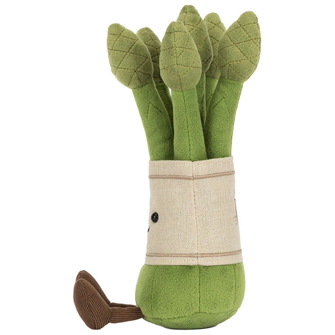 Jellycat knuffelplant asparagus, van de linkerzijkant gezien met een bruine voet en deels zichtbaar gezicht.