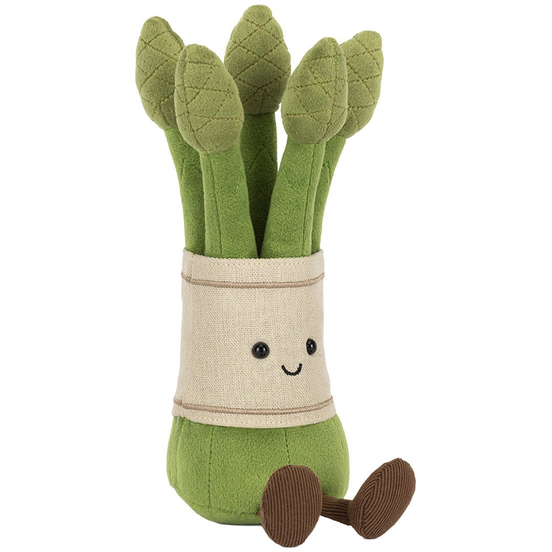 Jellycat knuffelplant asparagus met lachend gezicht en bruine voeten, schuin van voren gezien.