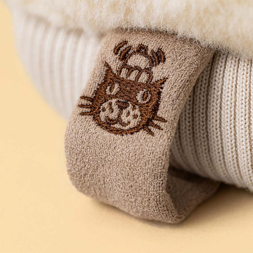 Detail van een label met een geborduurde kattenkop op de Jellycat pluchen winterwant.