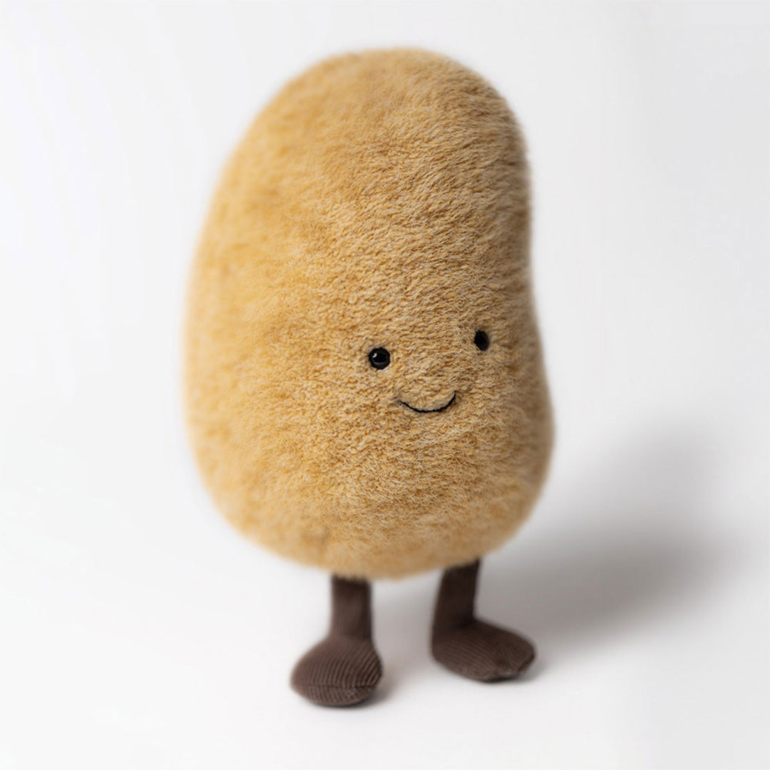 Jellycat knuffelaardappel Graham, beige met bruine benen, staat rechtop.