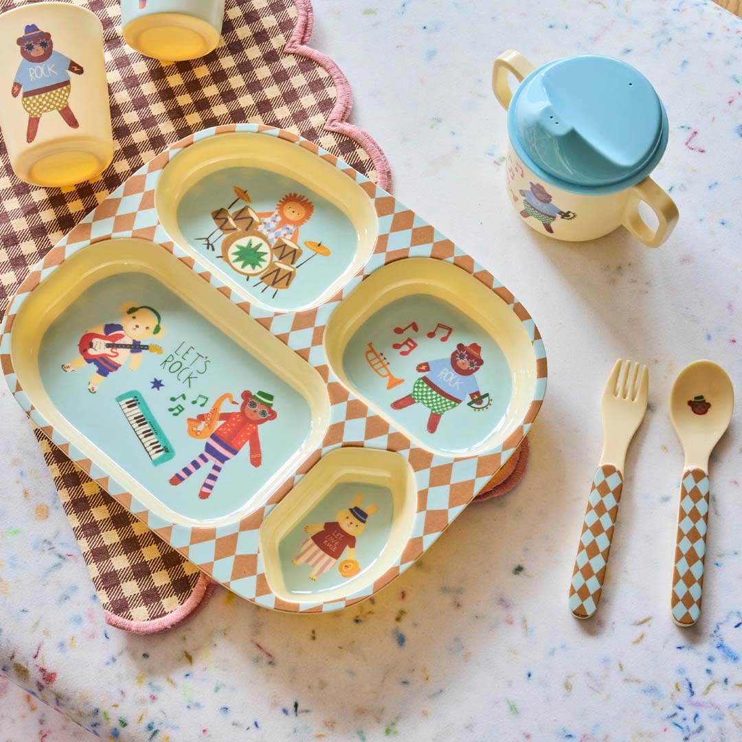 Rice kinderservies music band met een verdeeld bord, drinkbeker, lepel en vork, liggend op een geruite ondergrond.