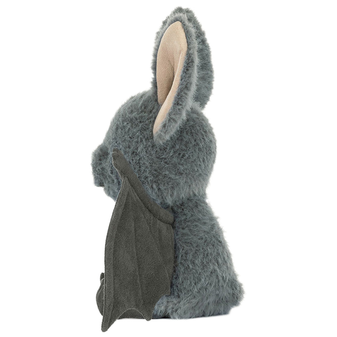 Jellycat pluchen vleermuis in grijs, zittend en van de zijkant gezien.