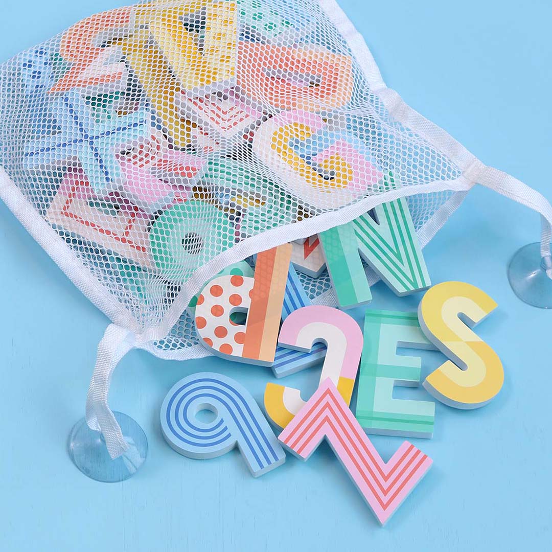 Een witte netzak met zuignappen, gevuld met a little lovely company badletters en -cijfers van schuim, die deels op een blauwe ondergrond liggen.