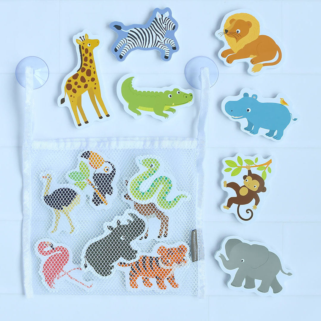 Drijvend badspeelgoed met safari dierenfiguren en een wit opbergnetje aan zuignappen op een witte tegelwand.