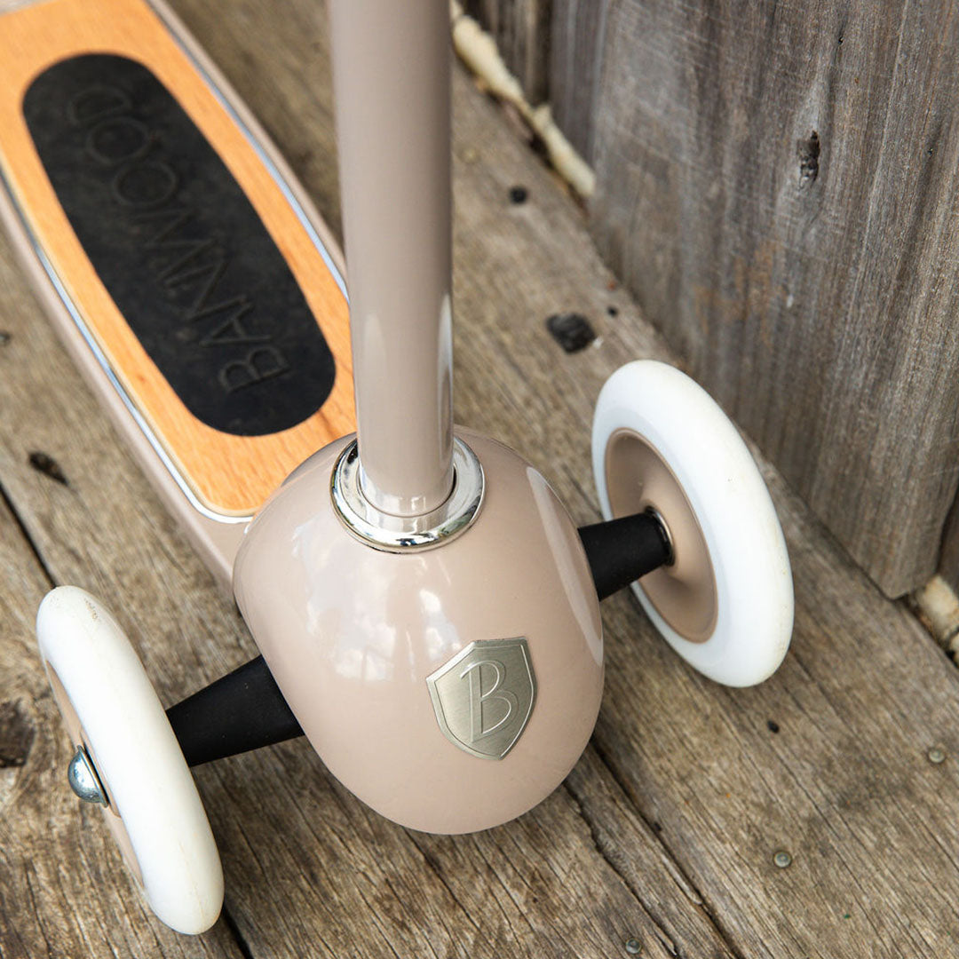 Detail van de voorkant van de Banwood kinderstep in beige met de twee voorwielen en het houten deck.