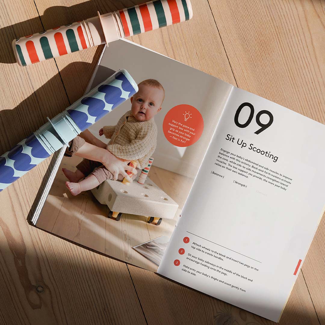 Een open instructieboekje van Modu met een afbeelding van een baby op een activiteitenspeelgoed en de activiteit 'Sit Up Scooting'.