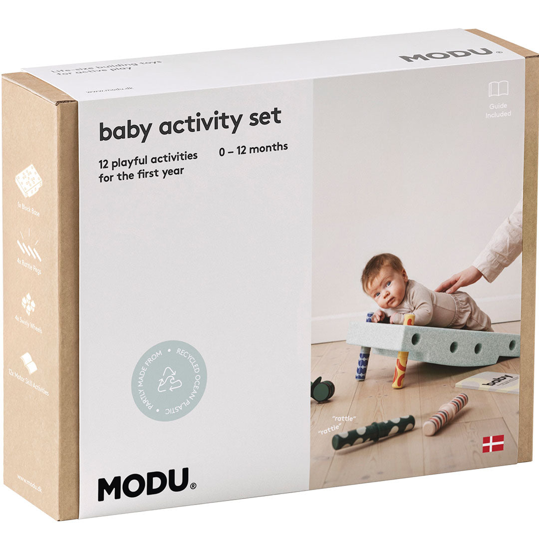 De voorkant van de Modu baby activiteitenset verpakking met een baby op een groen schuim speeltoestel.