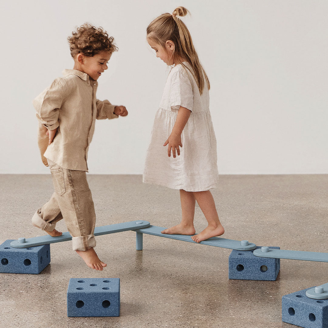 Twee kinderen balanceren op een Modu evenwichtsset opstelling die een zigzagparcours vormt.